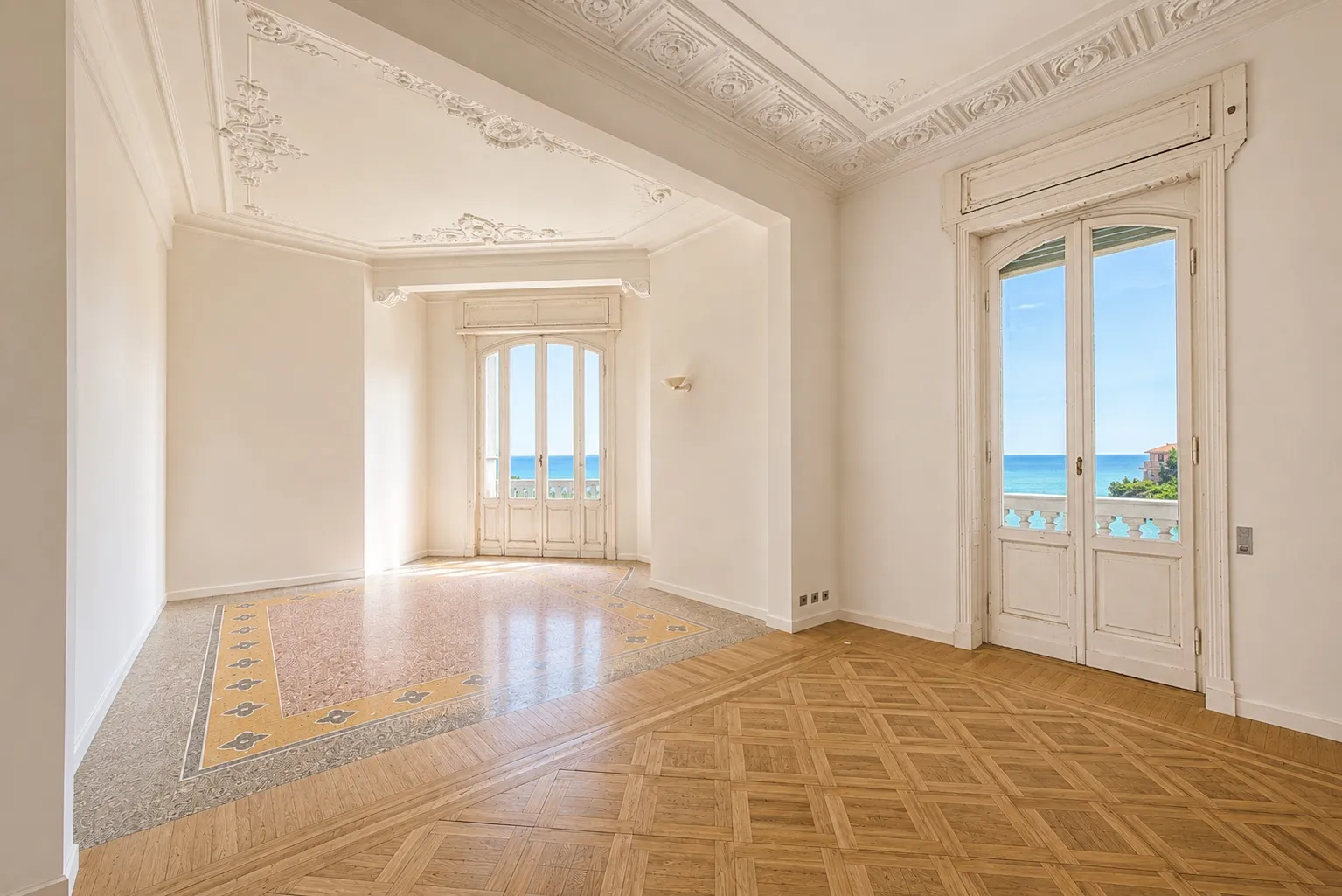 Salone con soffitti a stucco, pavimento alla veneziana e portefinestre sul mare
