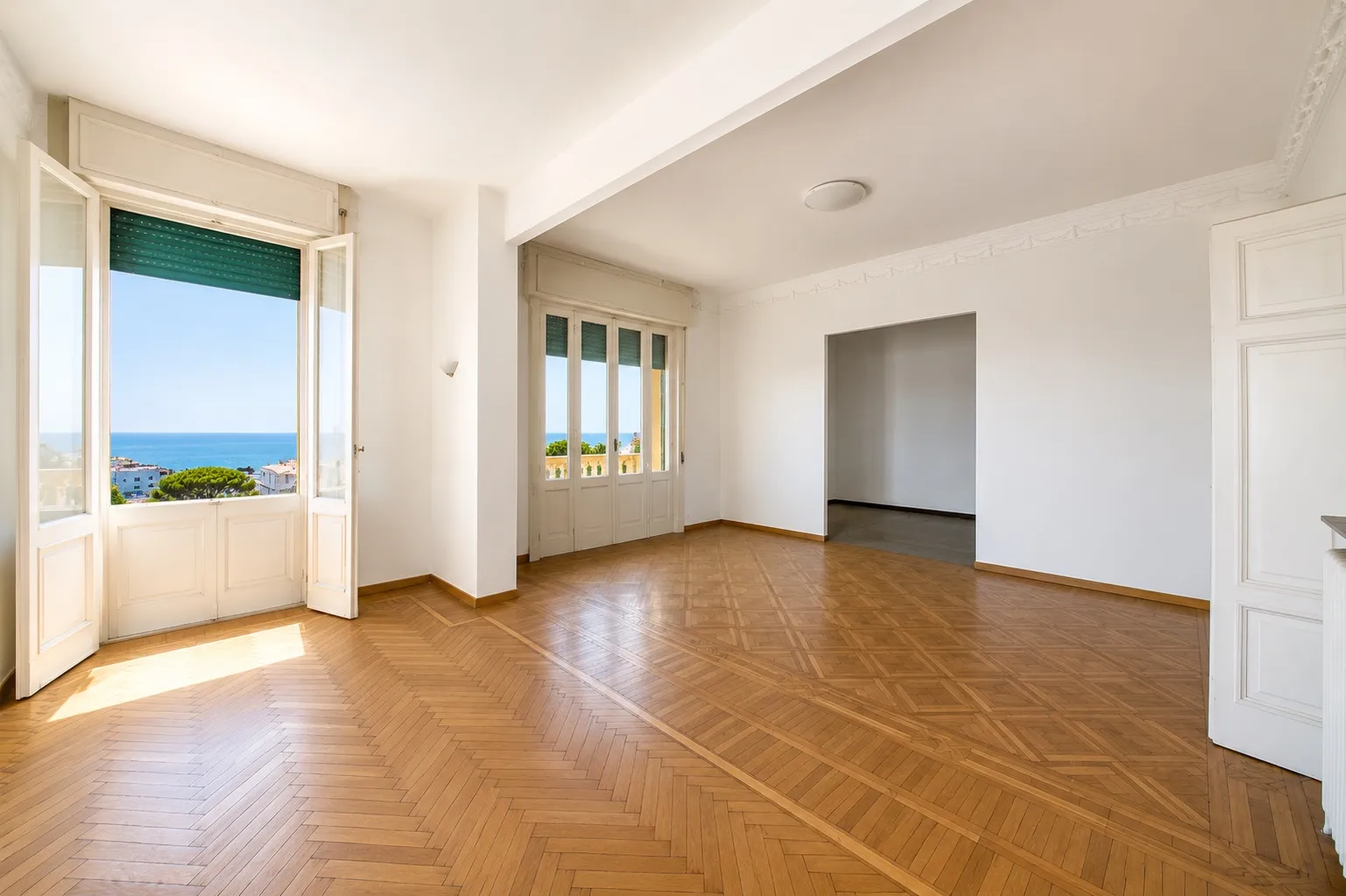 Soggiorno open space con parquet a spina e portafinestra vista mare
